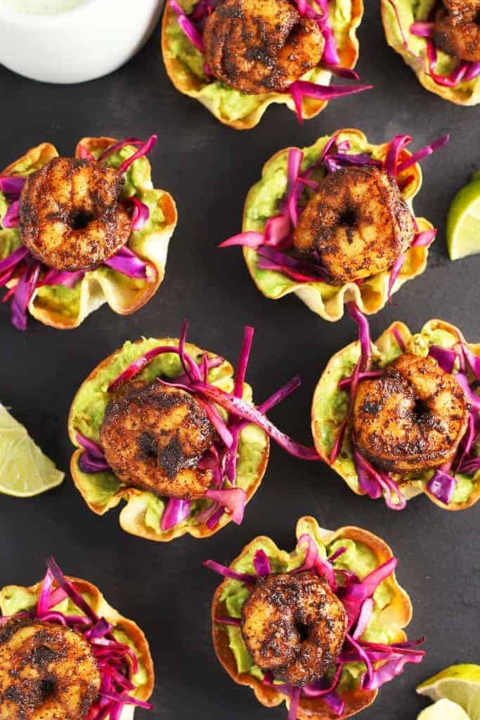 Wonton cups filled with guacamole and pickled cabbage and topped with a cooked shrimp