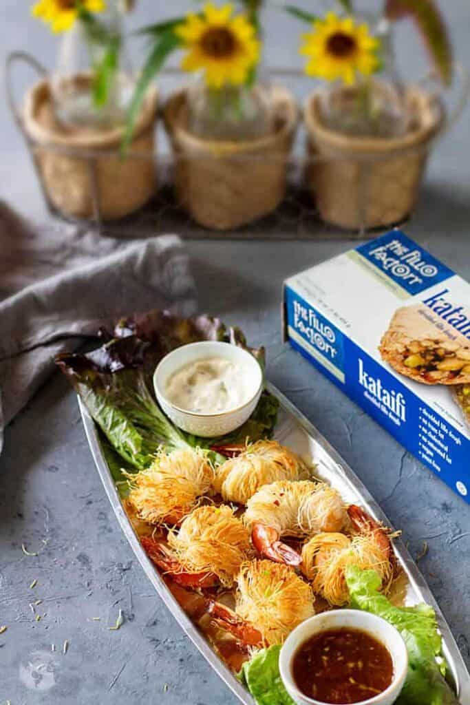 Breaded shrimp on a silver tray with 2 small bowls of sauce.