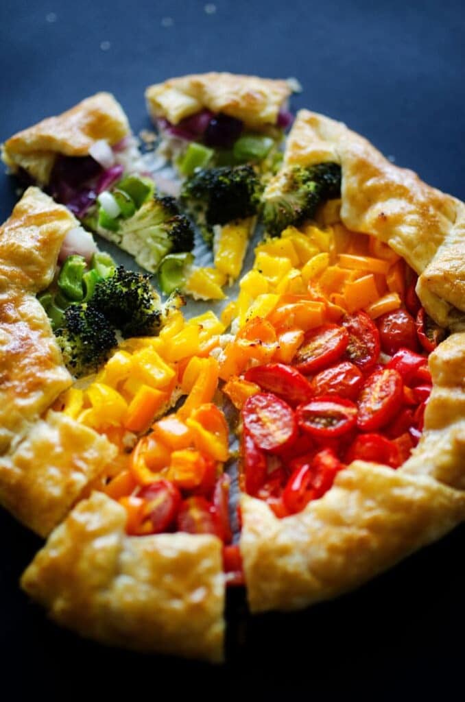 Top view of a tart with cherry tomatoes, yellow peppers and broccoli.