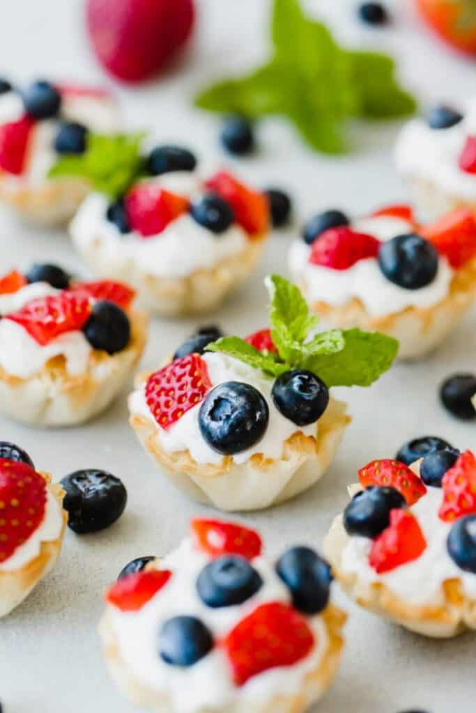 Greek yogurt fruit bites with blueberries and strawberries on top and a sprig of mint as a garnish. 