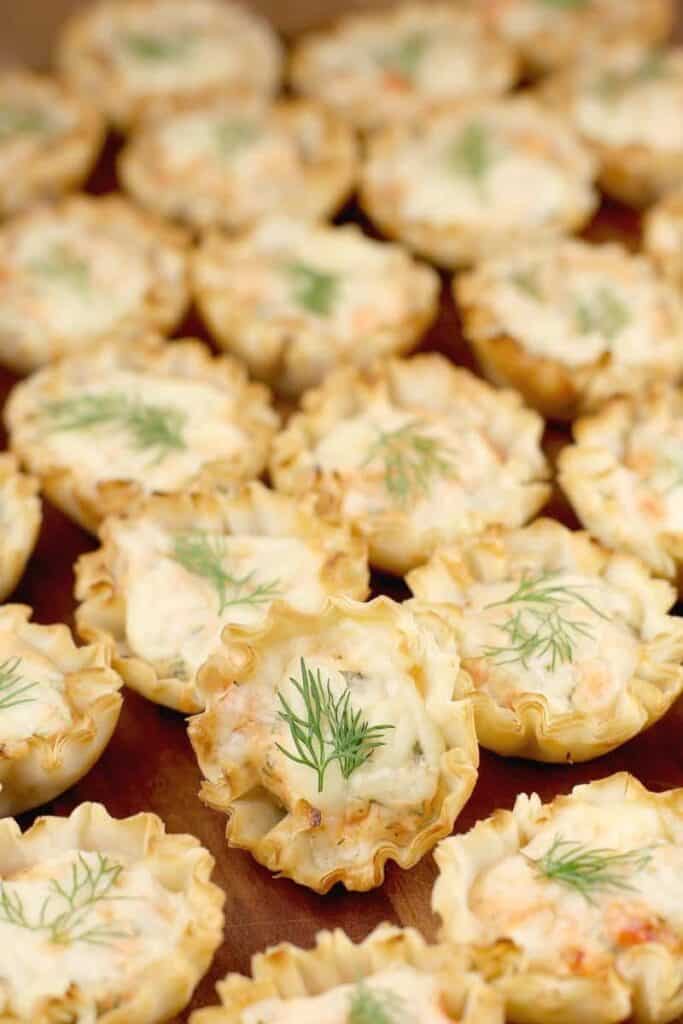 Rows of Smoked Salmon Mini Tarts garnished with a sprig of fresh dill.