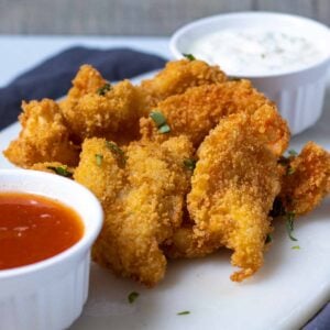 Crispy fried butterfly shrimp on table with sauces.