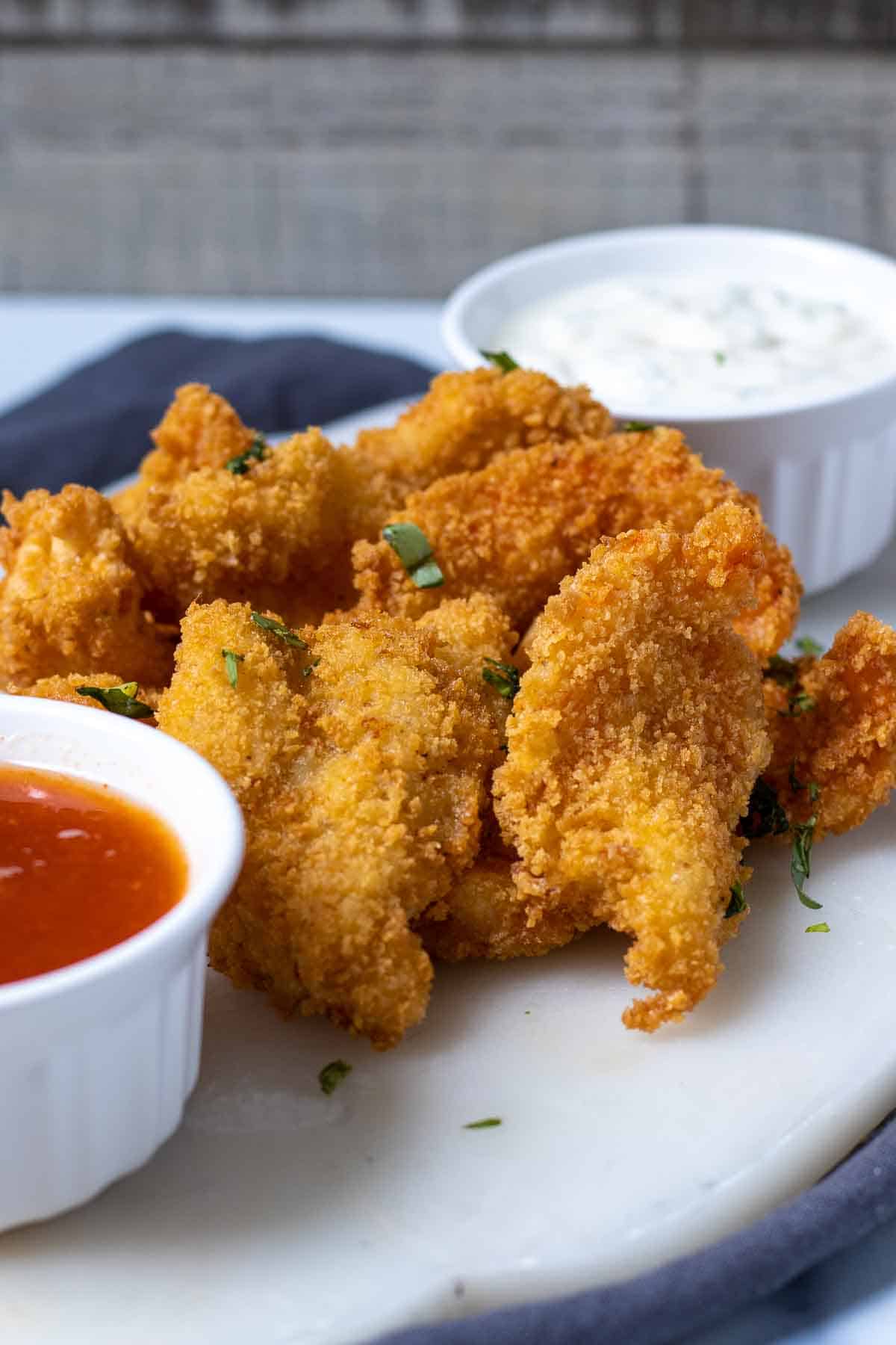 Crispy butterflied shrimp on table with sauces.