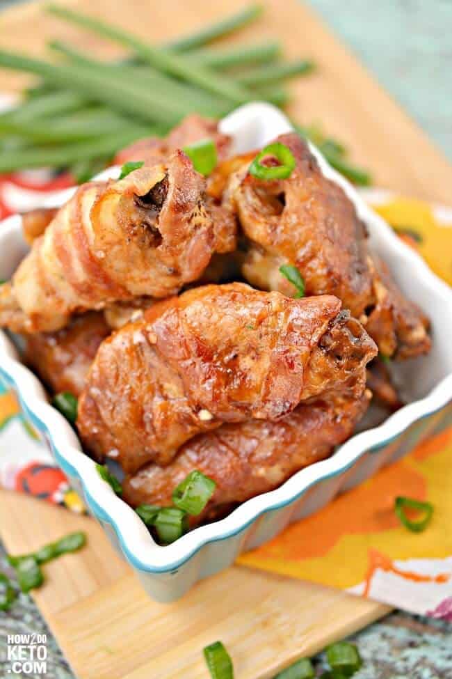 A square dish with bacon-wrapped chicken wings. 