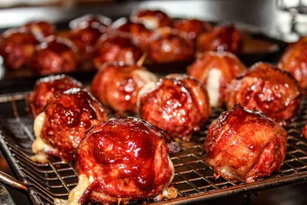 Bacon wrapped stuffed meatballs on a wire rack.