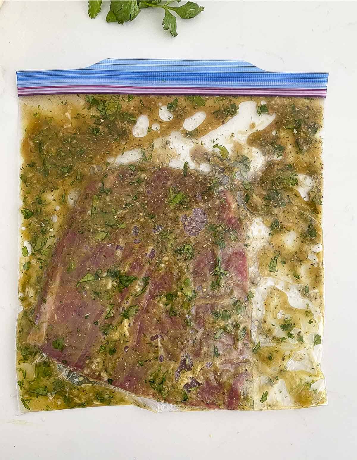 Flank steak with carne asada marinade in a plastic bag.