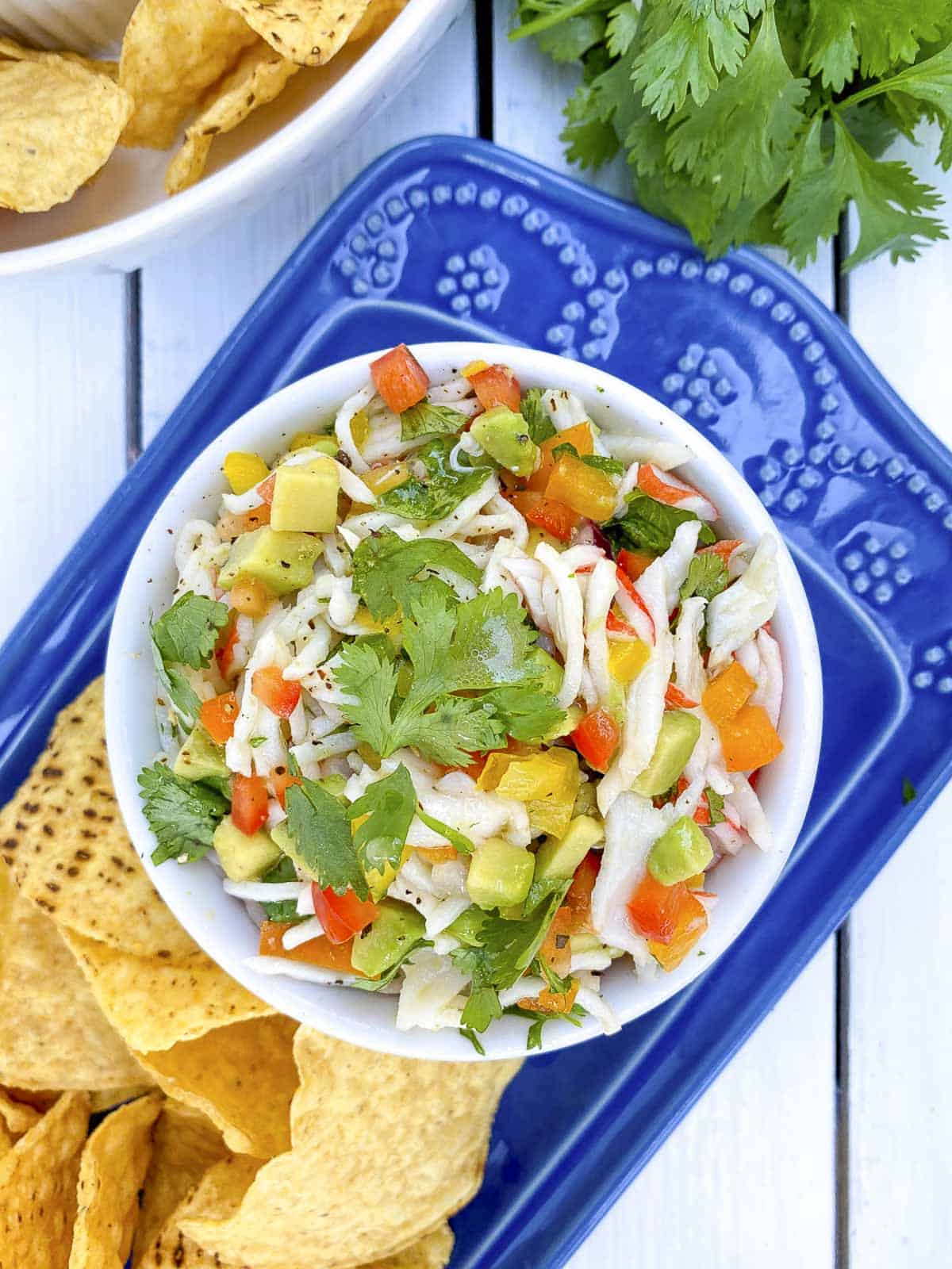 Closeup of crab ceviche in white bowl with chips on the side.