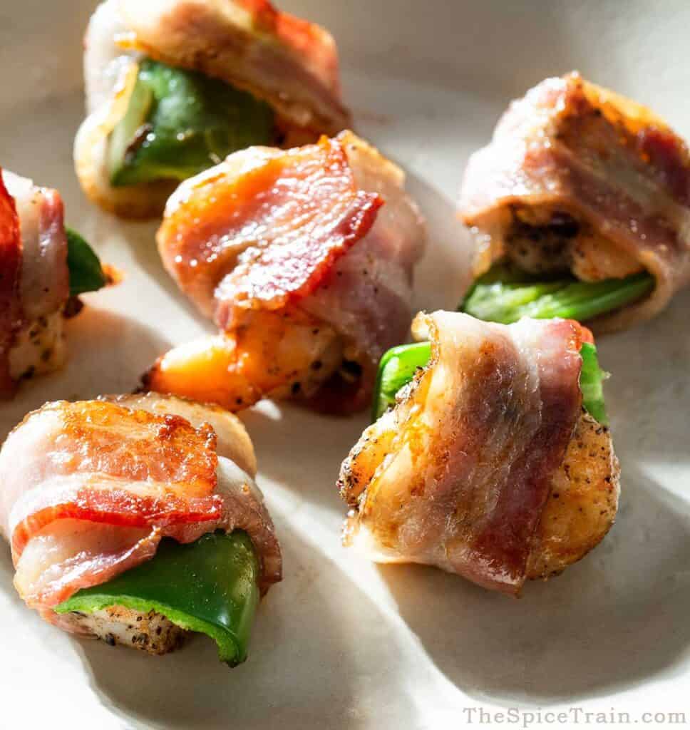 6 jalapeno bacon-wrapped shrimp on a white plate.
