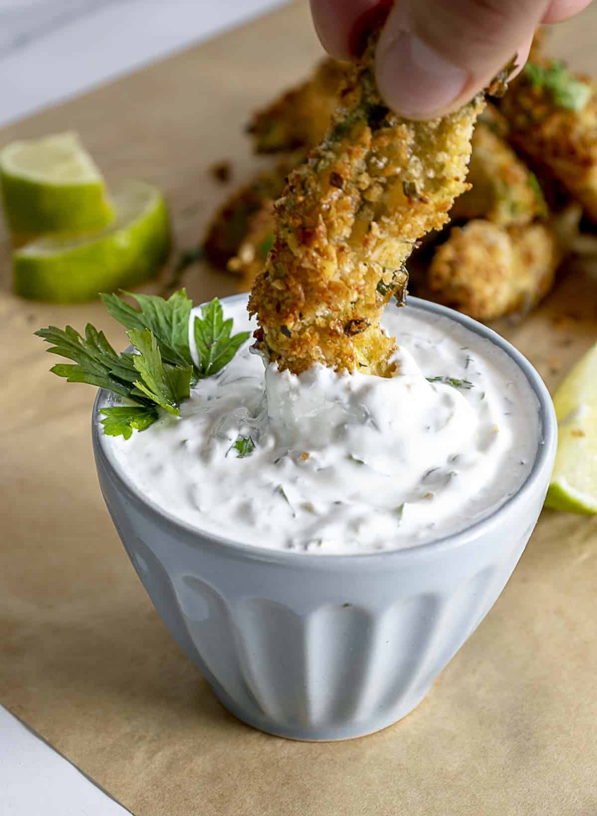 Dipping an avocado fry into the sour cream sauce.