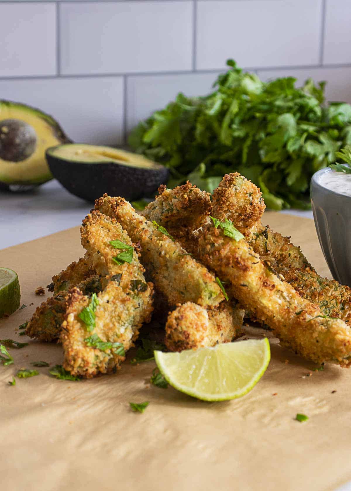 Crispy avocado fries on the table with dipping sauce on the side.