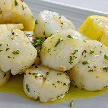 Angle shot of air fried lemon sage scallops with garlic on plate.