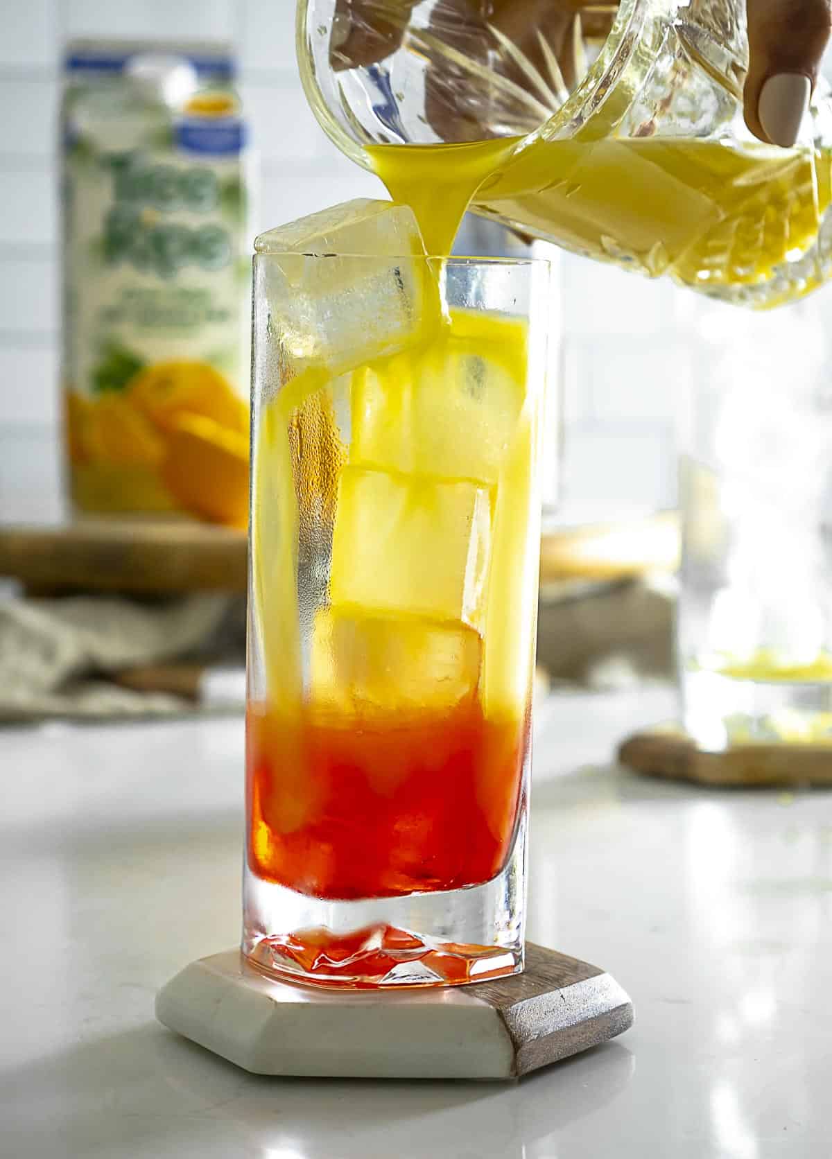 Pouring orange juice to top of drink.