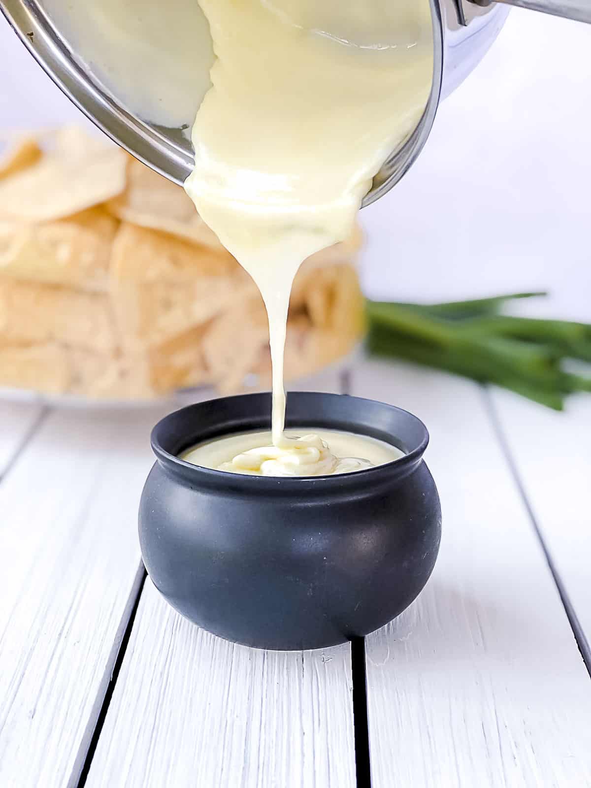 White cheese sauce without flour being poured into mini crock.