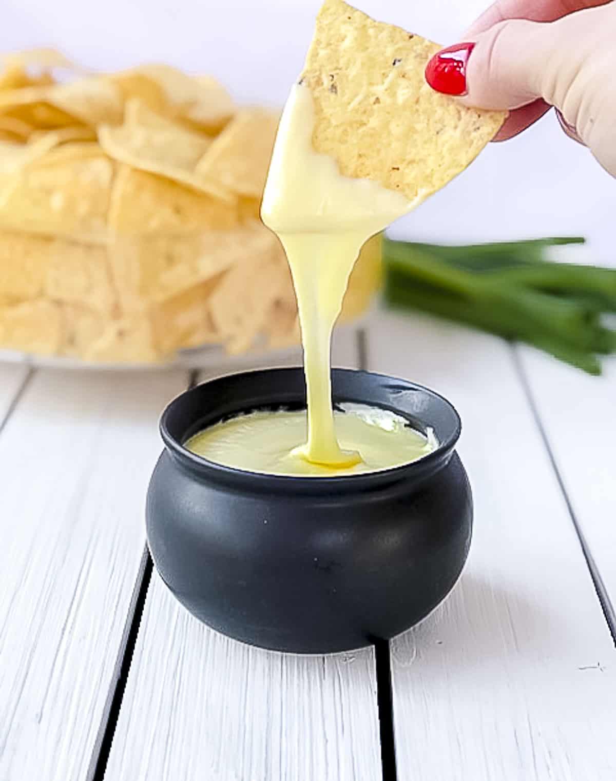 Dipping tortilla chip into flourless white cheese sauce.