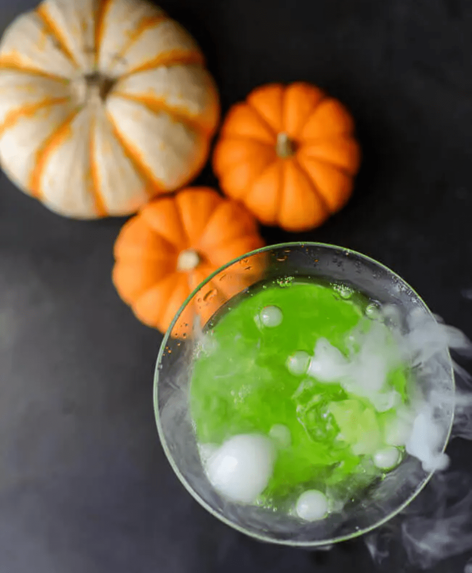 Bubbly green drink on table with pumpkins.