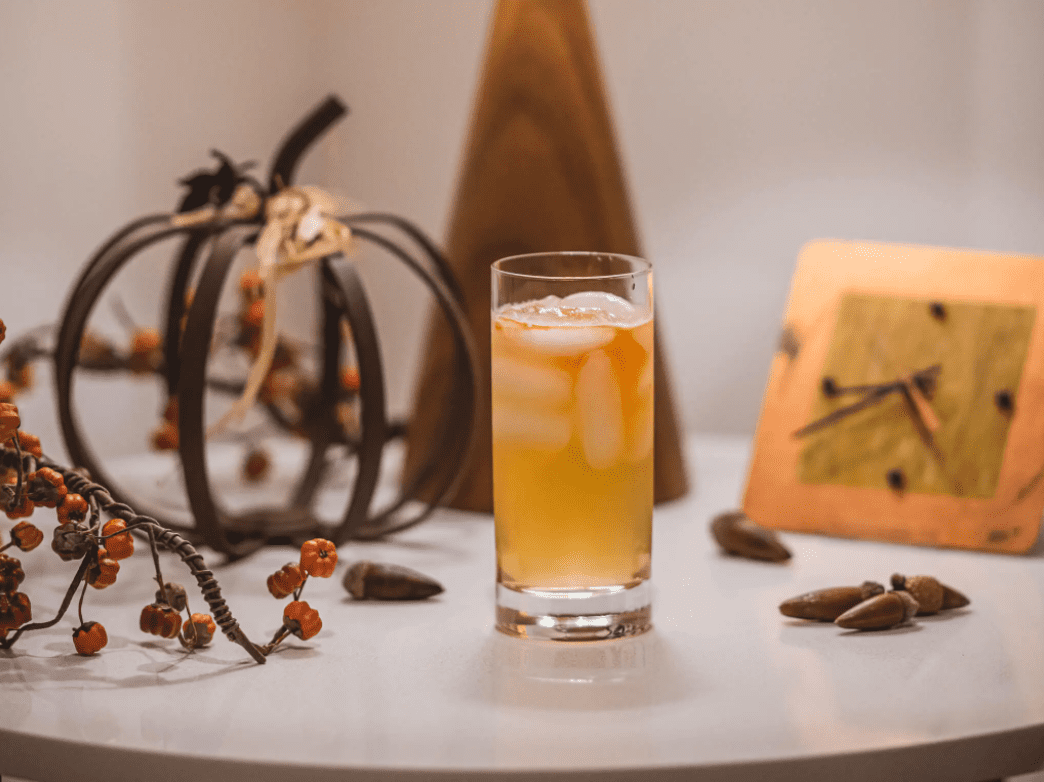 Orange cocktail on table with fall decorations.