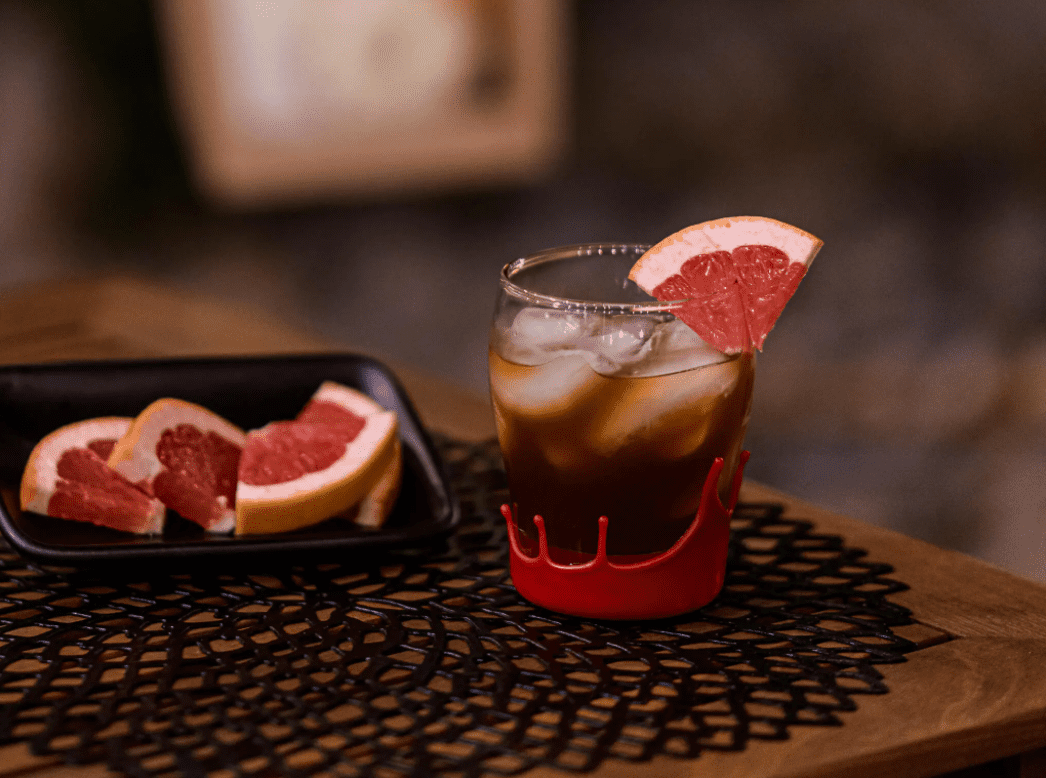 Dark cocktail on table with grapefruit slice.