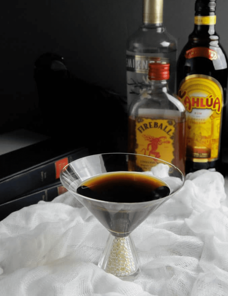 Coffee inspired cocktail with liquor bottles on a table with cloth.