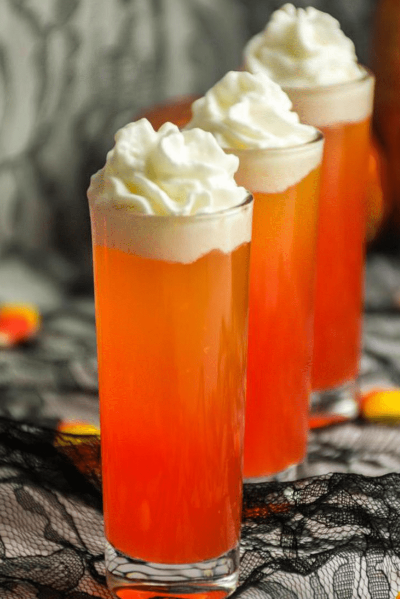 Orange candy corn theme shooters with whipped cream.