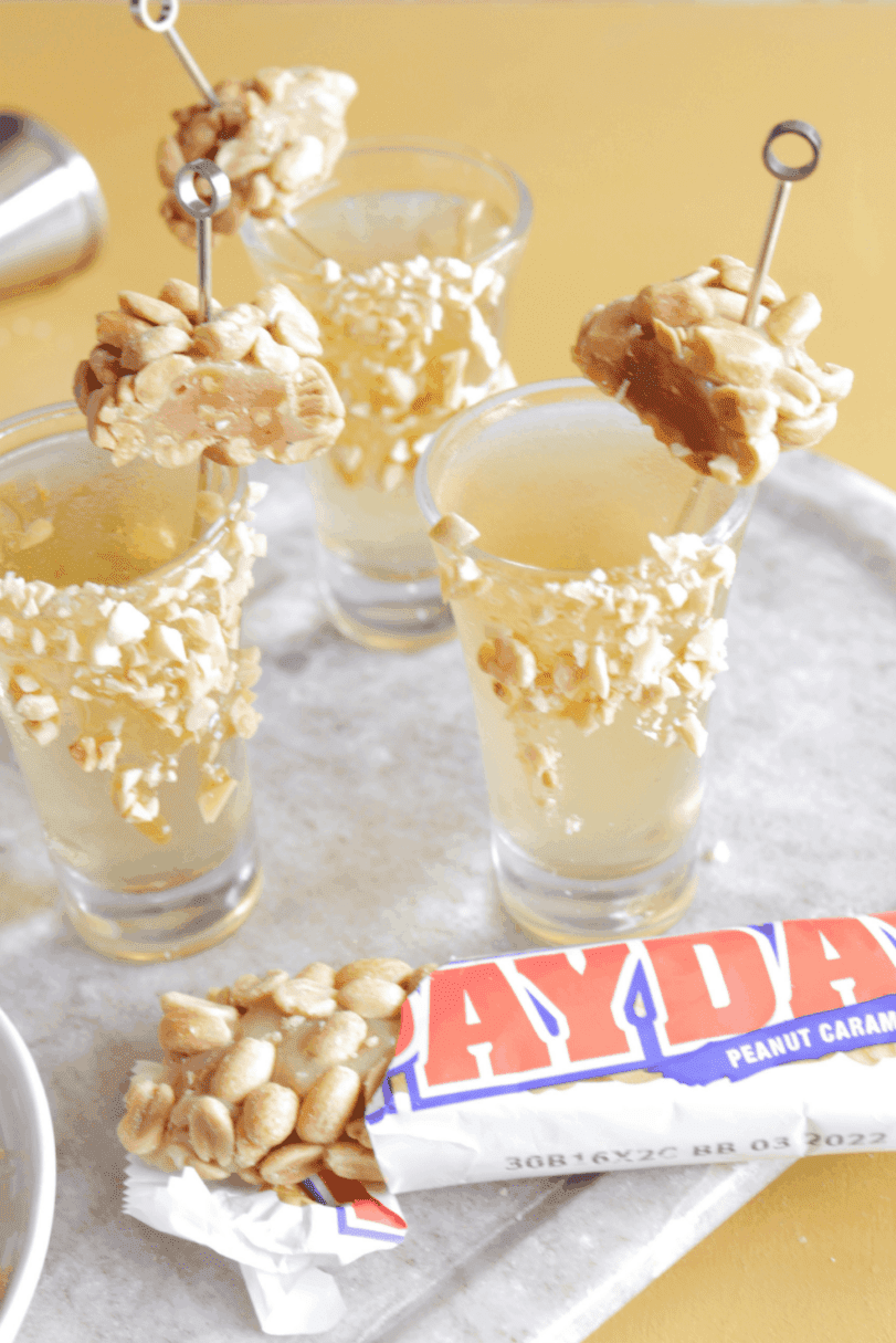 Candy themed vodka shooters with peanuts on a serving tray.