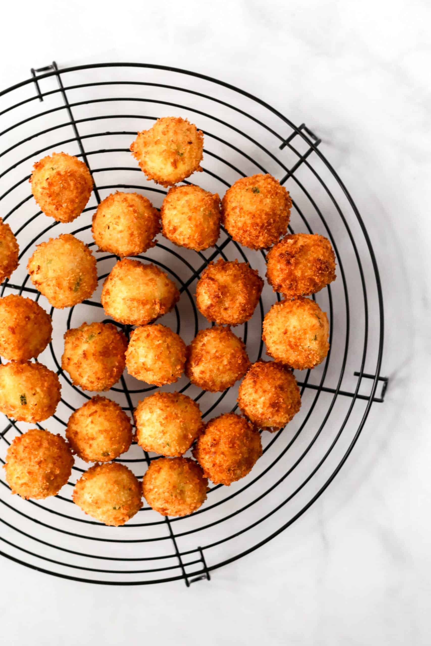 Fried cheesy potato croquettes on cooling rack.