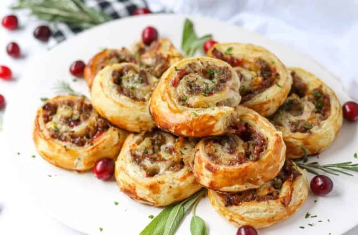 Pinwheels on a white plate with cranberries as decorations.