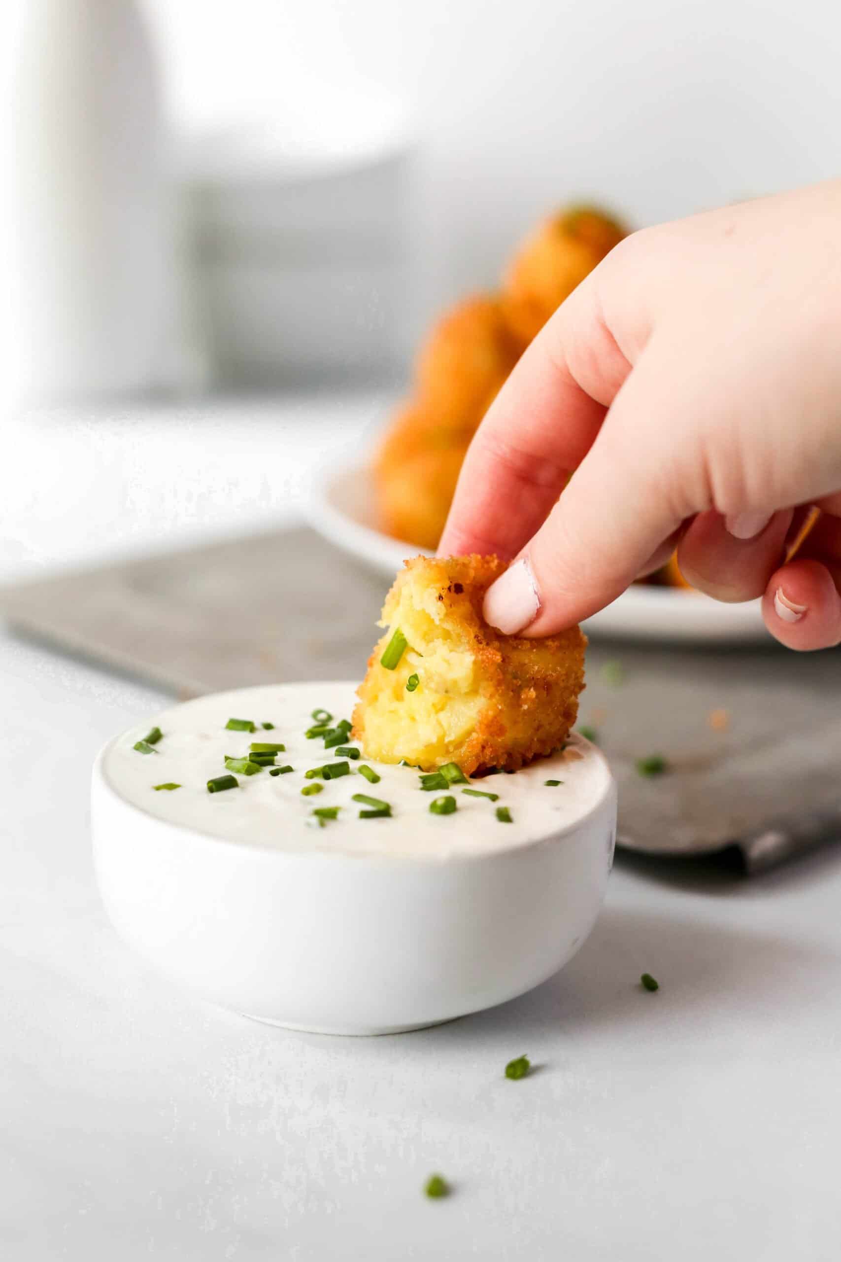 Potato croquettes dipping into sauce.