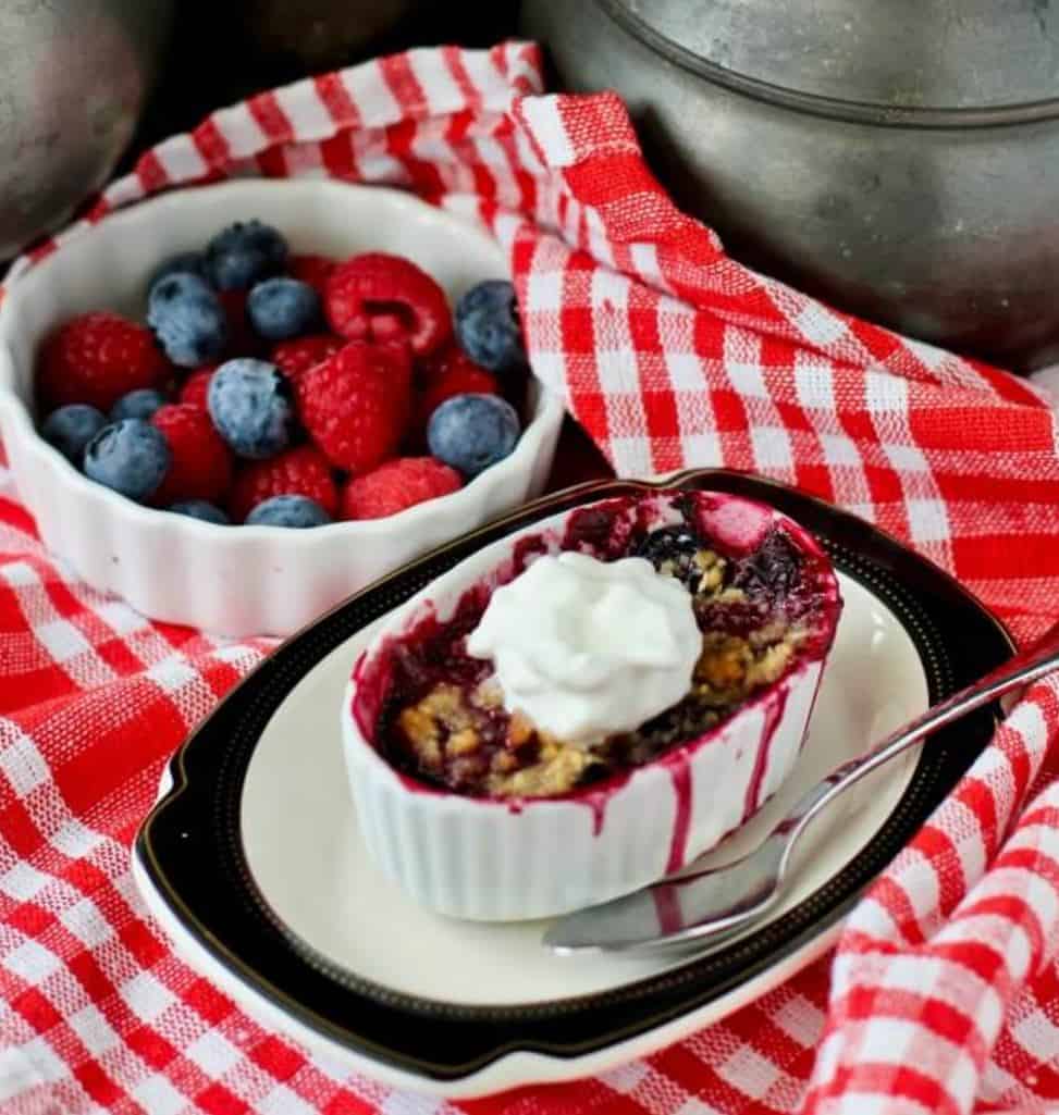 Dessert crips on checkered tablecloth with a bowl of berries. 