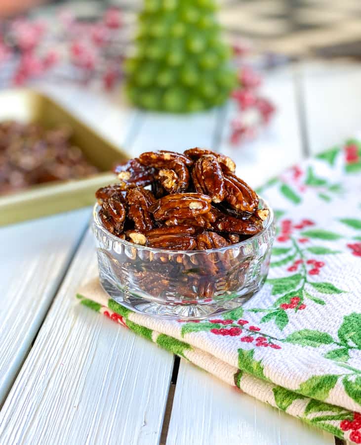 Shiny candied pecans in glass bowl on table.