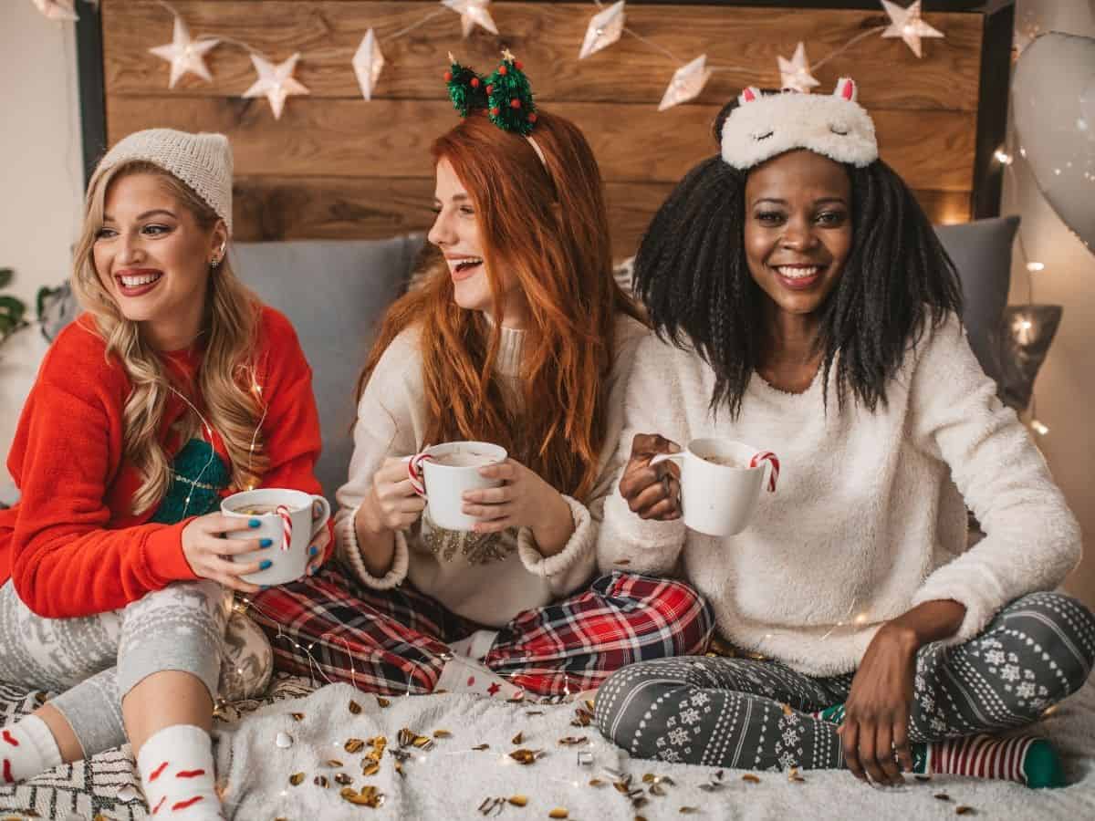 Women in pajamas at a Christmas party sipping hot cocoa.