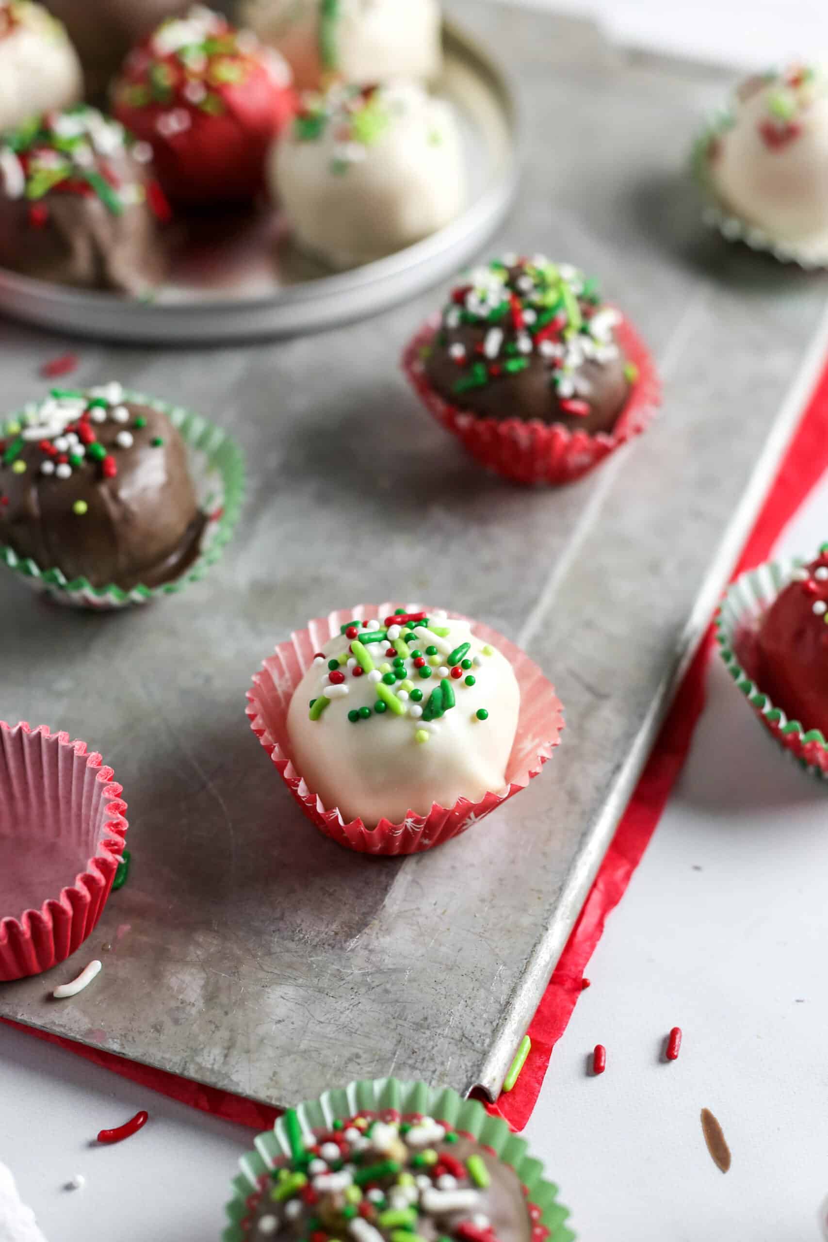 Festive cake balls in mini muffin cups on sheet pan.