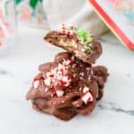 Crockpot Christmas crack candy stacked on table with peppermint and sprinkles.