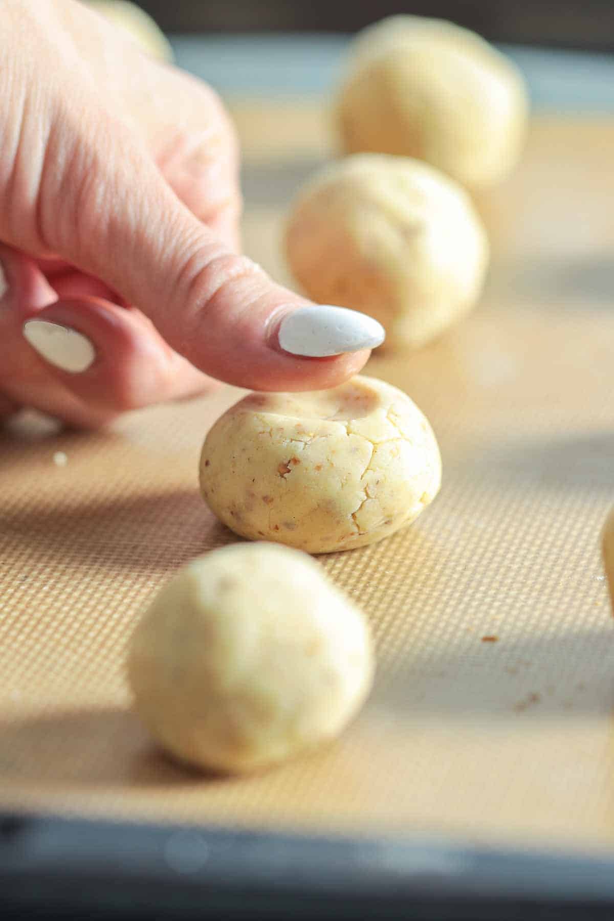 Pressing kourabiedes Greek cookie dough on baking sheet.