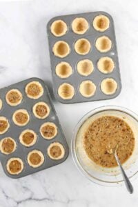 Muffin tin with dough and filling.