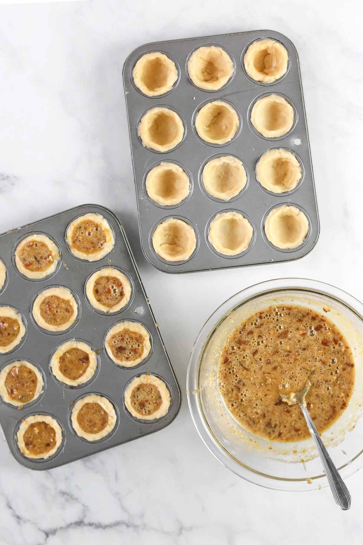 Filling pecan tassies with pecan filling in mini muffin tins.