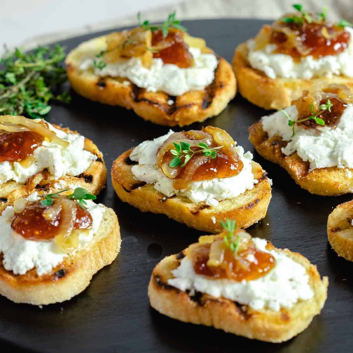 Fig goat cheese crostini appetizer on cutting board.