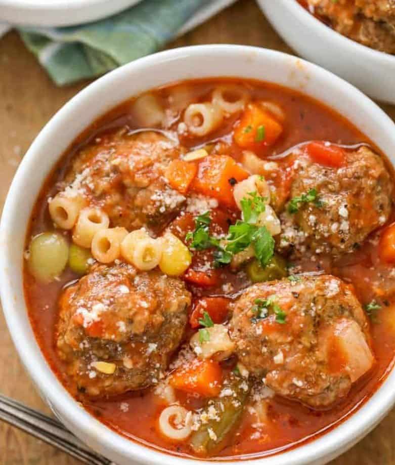 Meatball soup with noodles and veggies in a white bowl. 