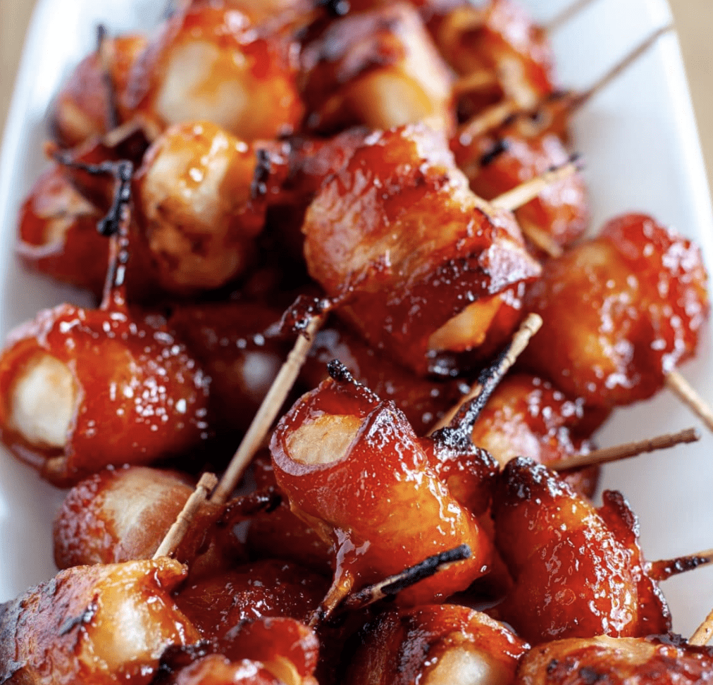 Bacon wrapped water chestnuts on a white plate.