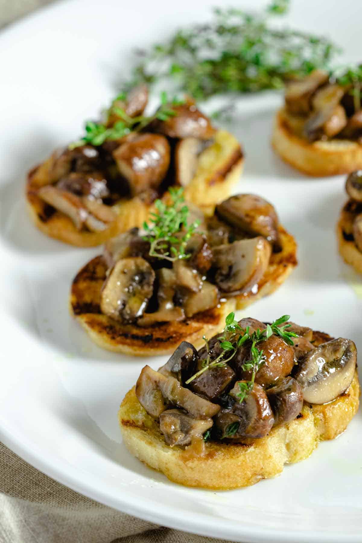 Mushroom appetizer served on bread with thyme.