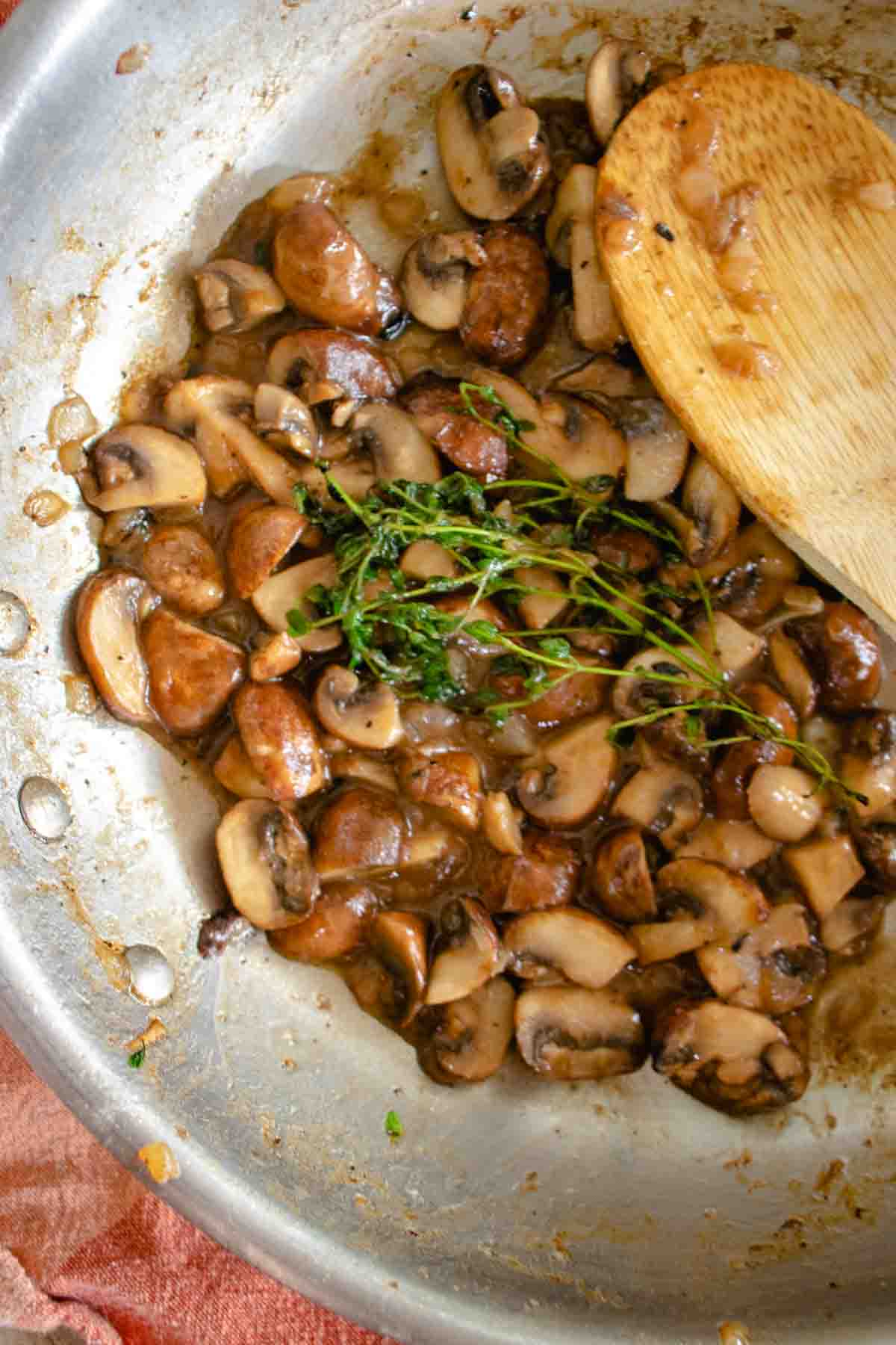 Mushrooms sauteed in saucepan with thyme.