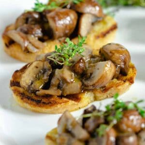 Mushroom bruschetta on a plate with fresh thyme.