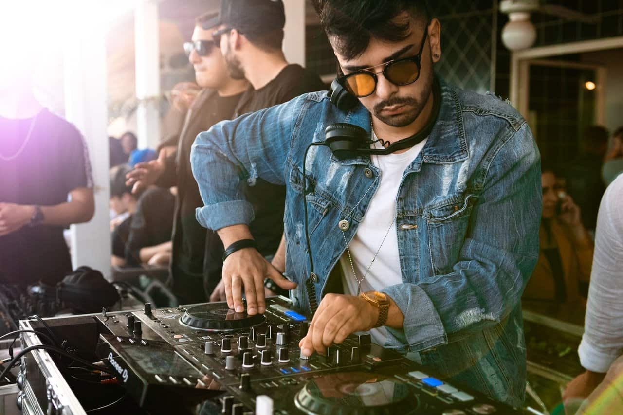 Man Wearing Blue Denim Jacket While Using Black Dj Controller.