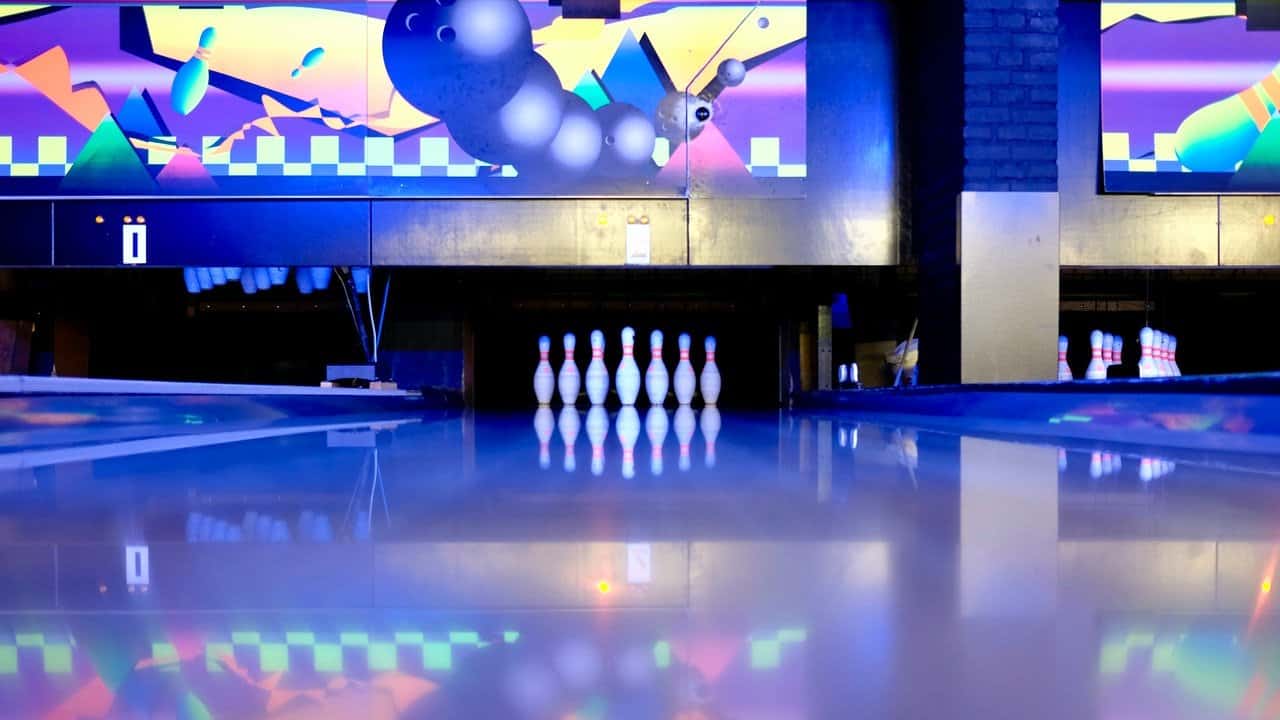 Bowling pins set on ground in neon bowling lane.