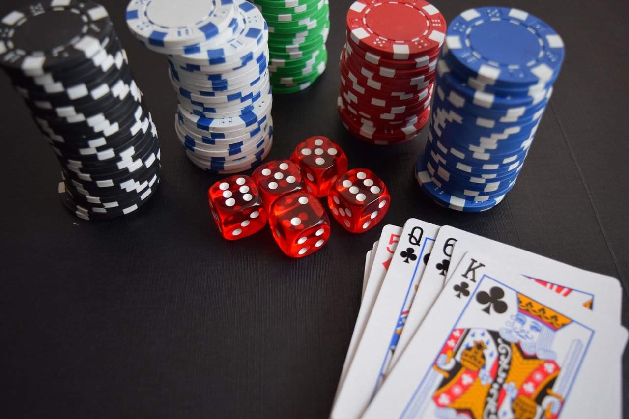 Playing cards, poker chips, and dice on black table.