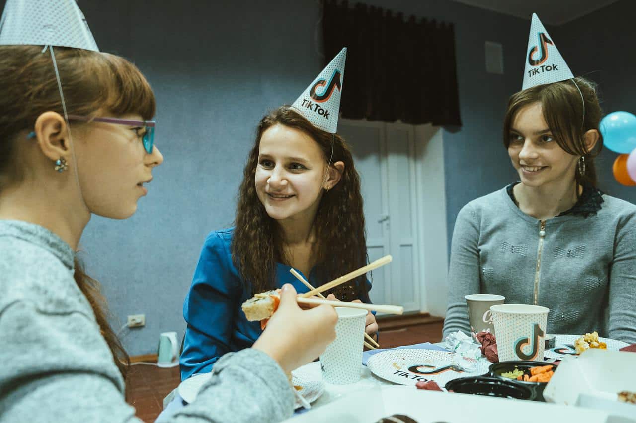 Three teen girls celebrating at a TikTok themed party.