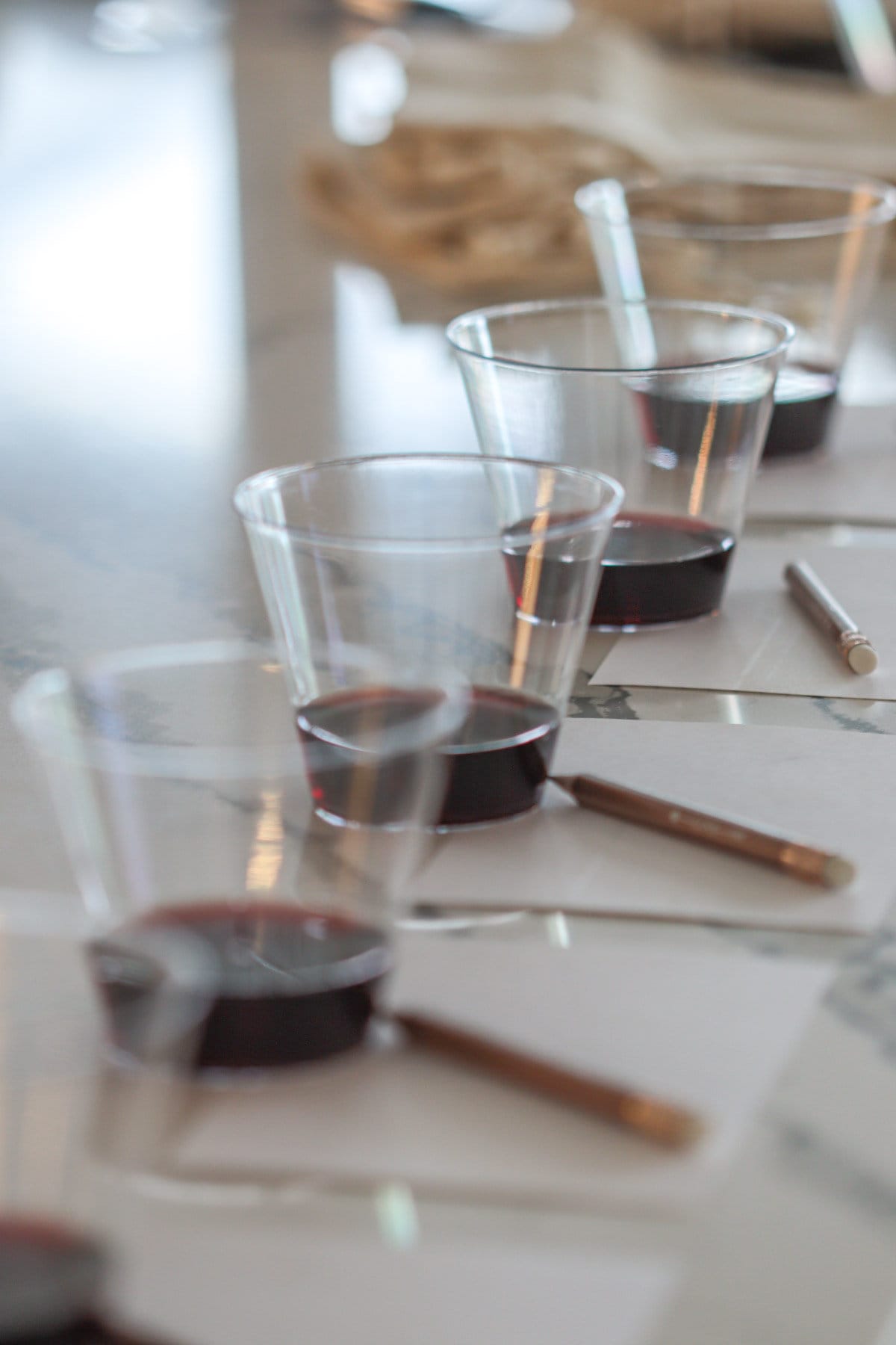 Wine in glasses with pencil and paper on table.