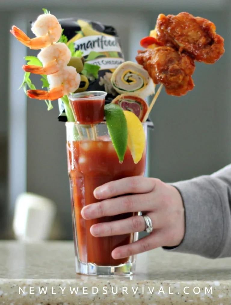 Bloody mary cocktail garnished with shrimp, chicken wings, popcorn, tortilla and cocktail sauce.