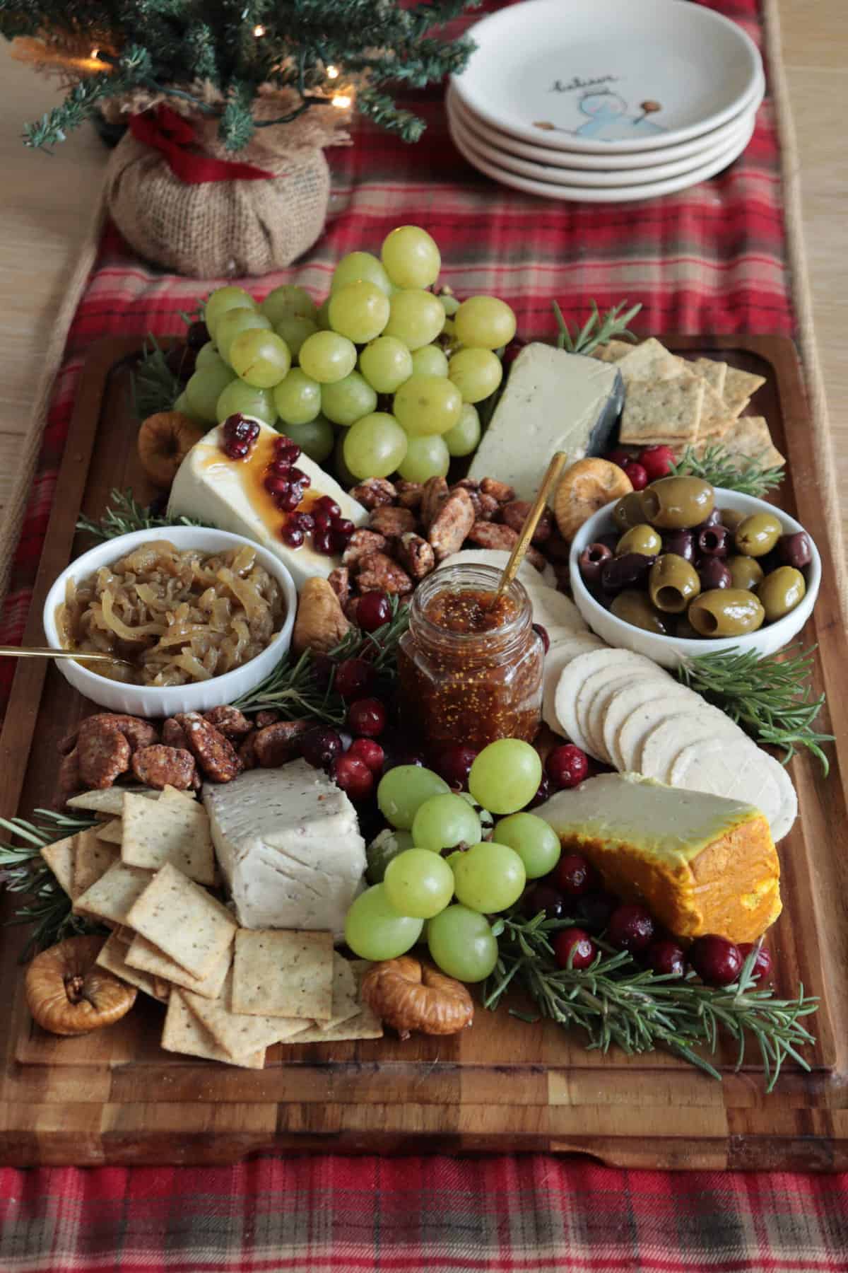 Cheese board with grapes, olives, herbs and crackers.