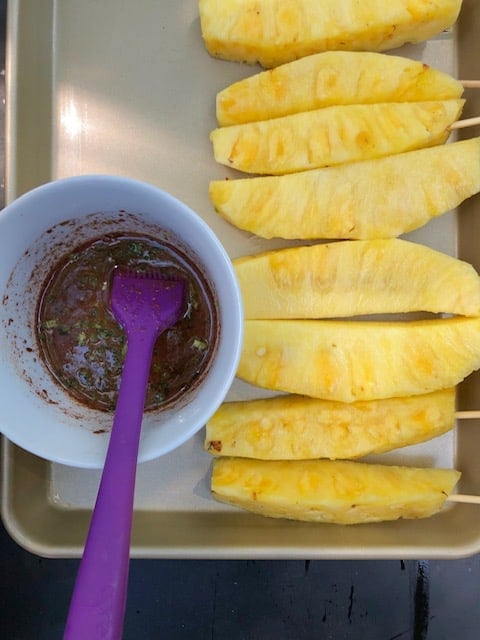 Pineapple glaze next to pineapple wedges.