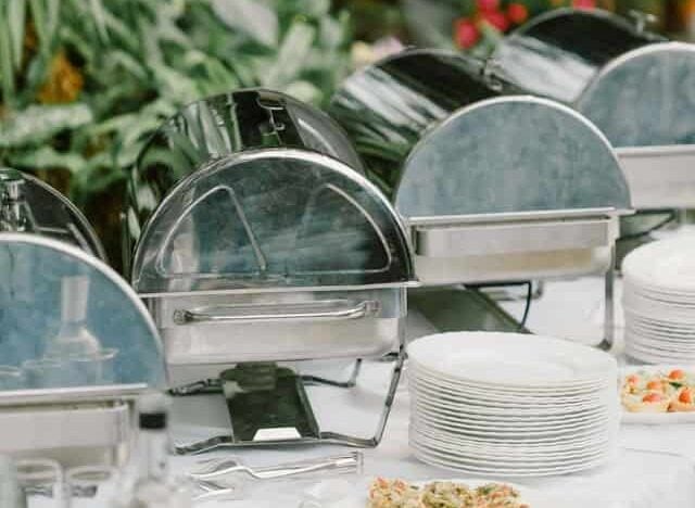 Banquet table with chafing dishes and food.